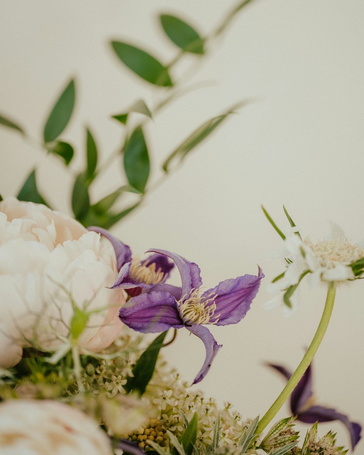 Ivory peonies and lilac clematis in an editorial floral arrangement